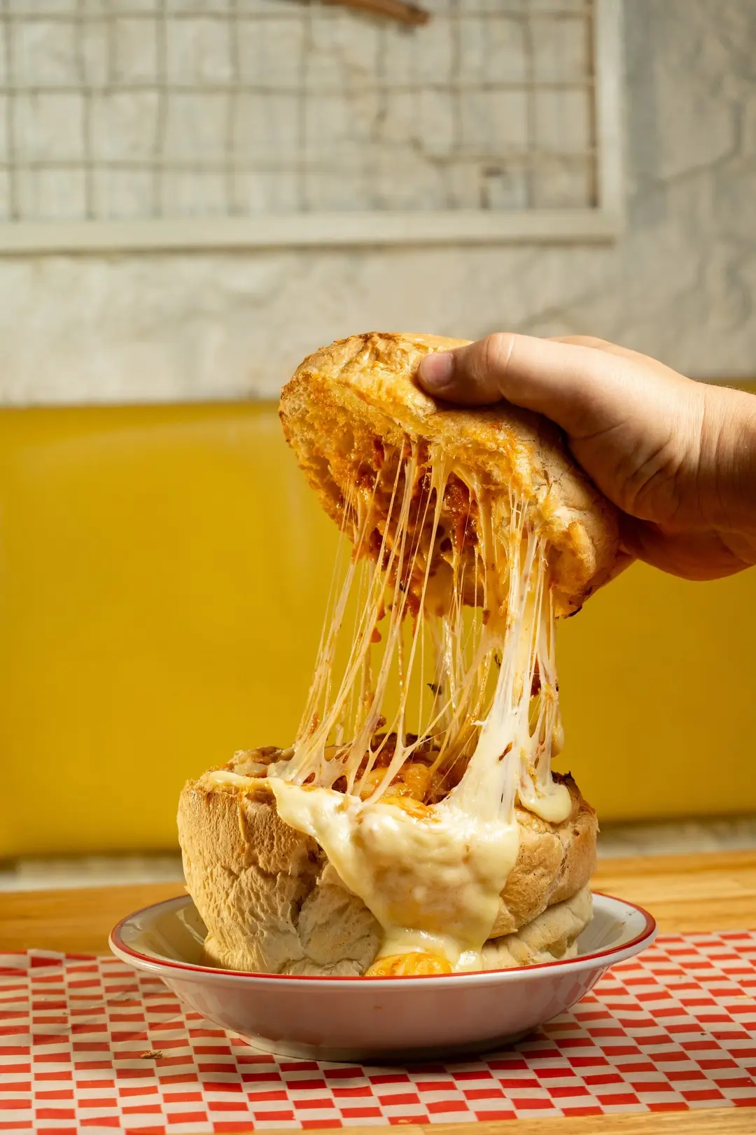 Una mano levanta la tapa del volcán y el queso se estira