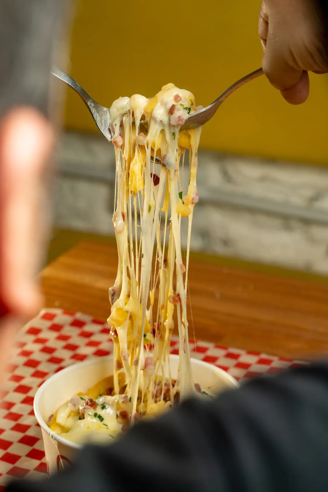 Dos tenedores estiran el queso de un Mac & Cheese
