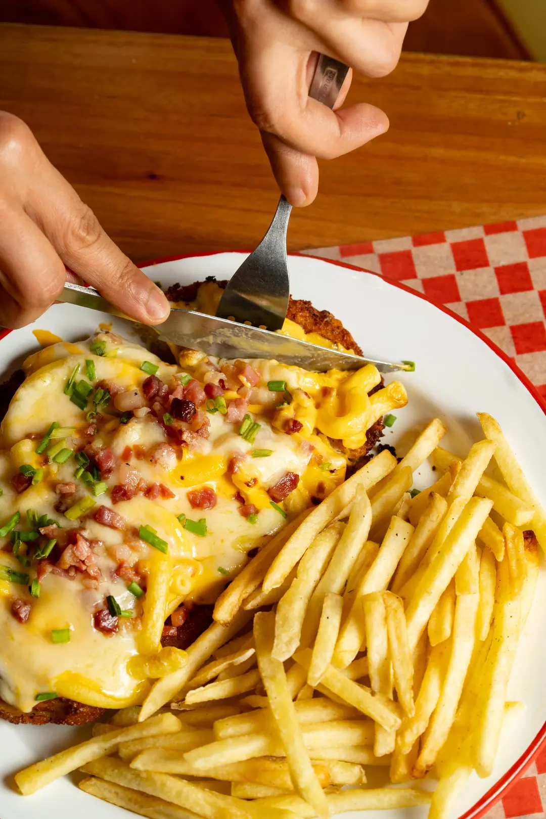 Cortando una milanesa gratinada con papas fritas